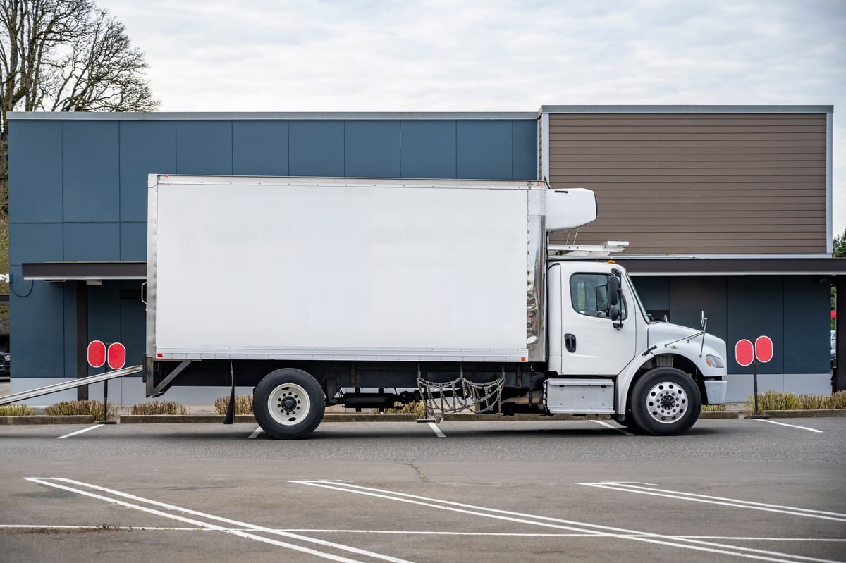 Commercial box truck and trailer with fleet graphics parked at a distribution facility